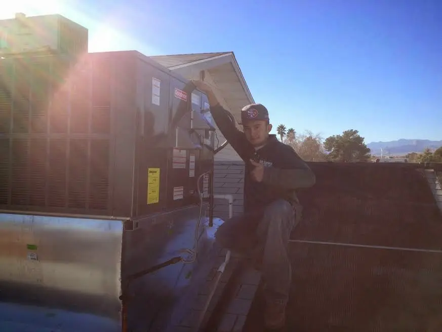 HVAC technician performing AC Tune-Up on a rooftop unit in Templeton